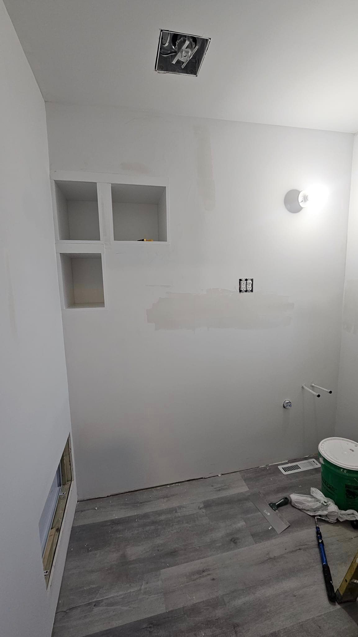 A bathroom under construction with a green bucket on the floor.