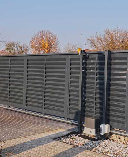 Gabion. Automatic entrance gate used in combination with a wall made of gabion.