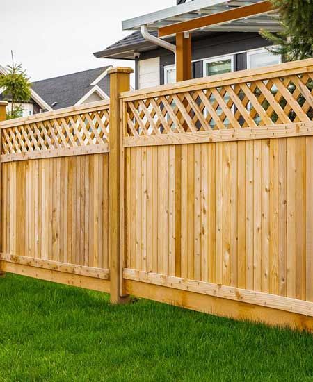 Nice wooden fence around house. Wooden fence with green lawn. 
