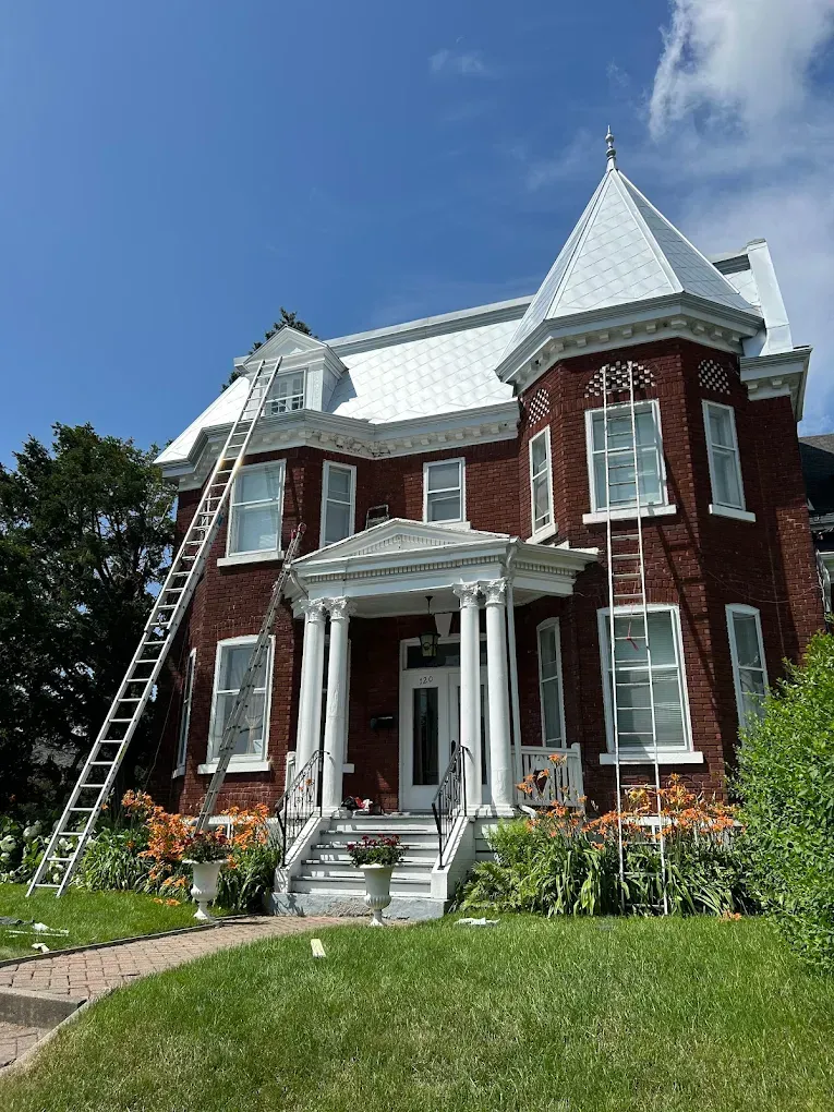 Peinture extérieure sur maison en briques rouges avec toit blanc