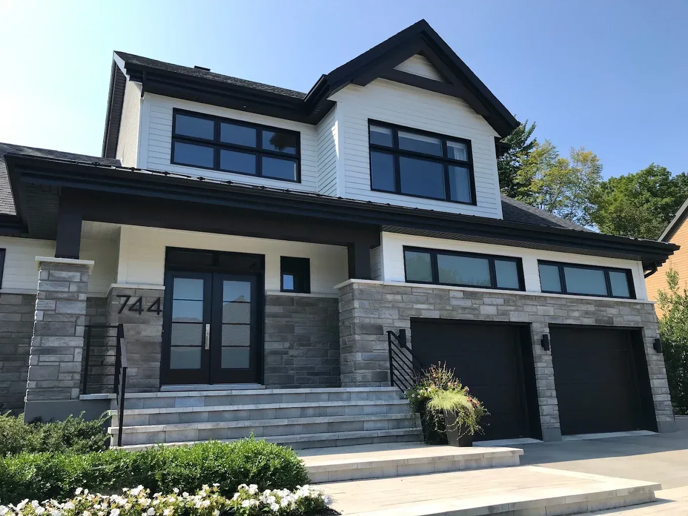 Une grande maison blanche avec un toit noir et deux garages, peinture residentielle