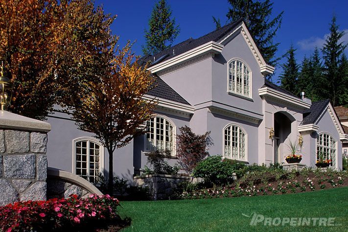 Peinture extérieure professionnelle sur grande maison avec pelouse verdoyante