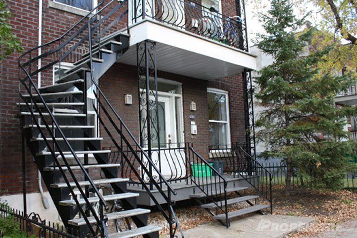 Peinture d’un escalier en fer forgé sur bâtiment en briques avec accès au deuxième étage.