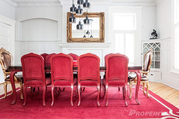 Une salle à manger avec une longue table et des chaises rouges, finition intérieure maison de prestige