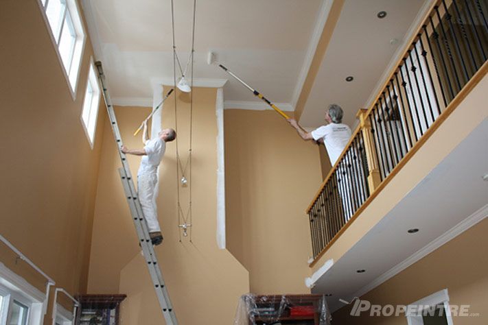 Deux peintres appliquent une finition intérieure dans un condo moderne.