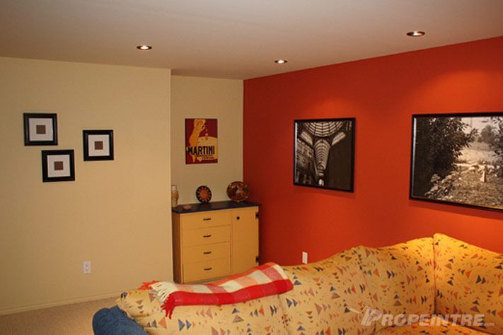 Sous-sol rénové avec mur d’accent orange et encastrés modernes, projet signé Propeintre