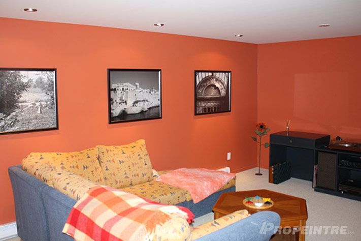 Mur accent orange et ambiance moderne dans un espace télé de sous-sol fraîchement peint