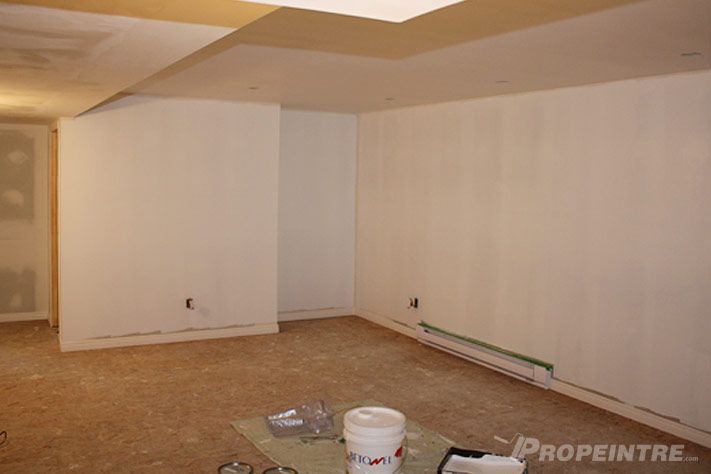 Sous-sol en cours de rénovation avec nouveau plafond suspendu et murs prêts à peindre