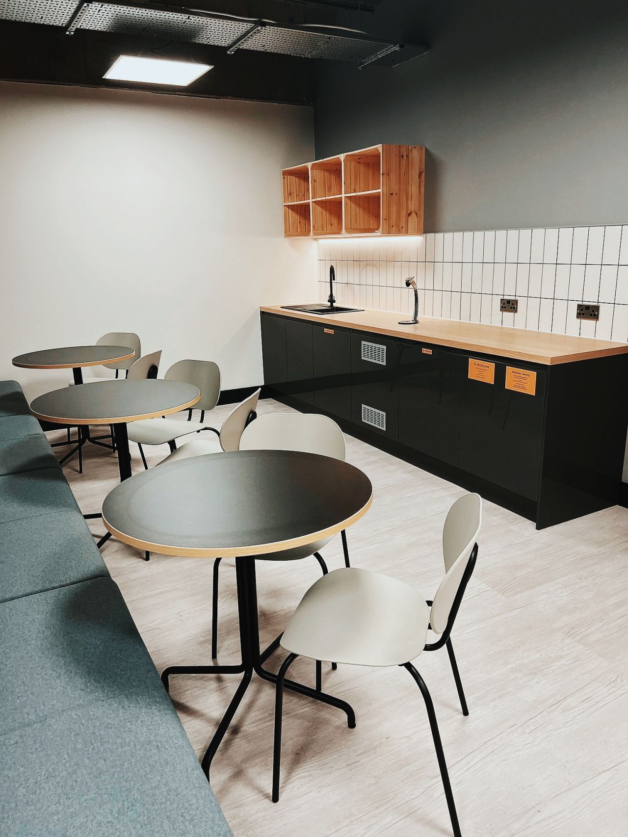 A room with tables and chairs in it and a kitchen.