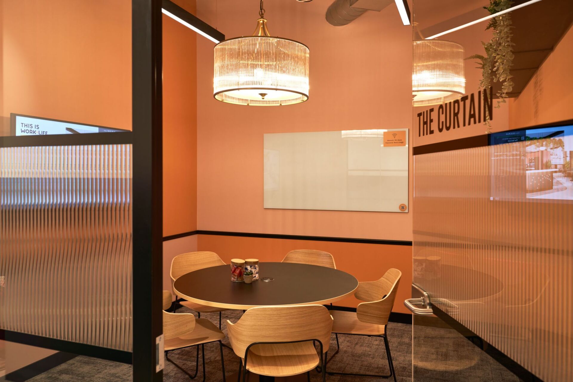 A meeting room with a round table and chairs and a whiteboard.