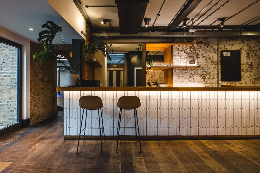 A bar with two stools in a room with a brick wall.