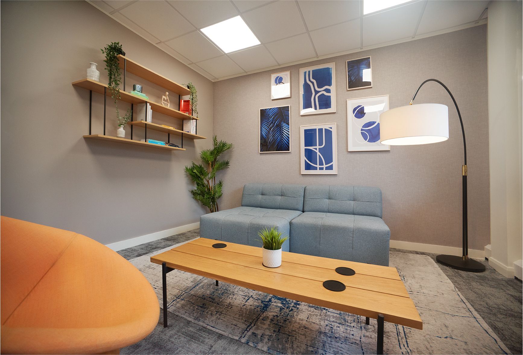 A living room with a couch , coffee table , chair and lamp.