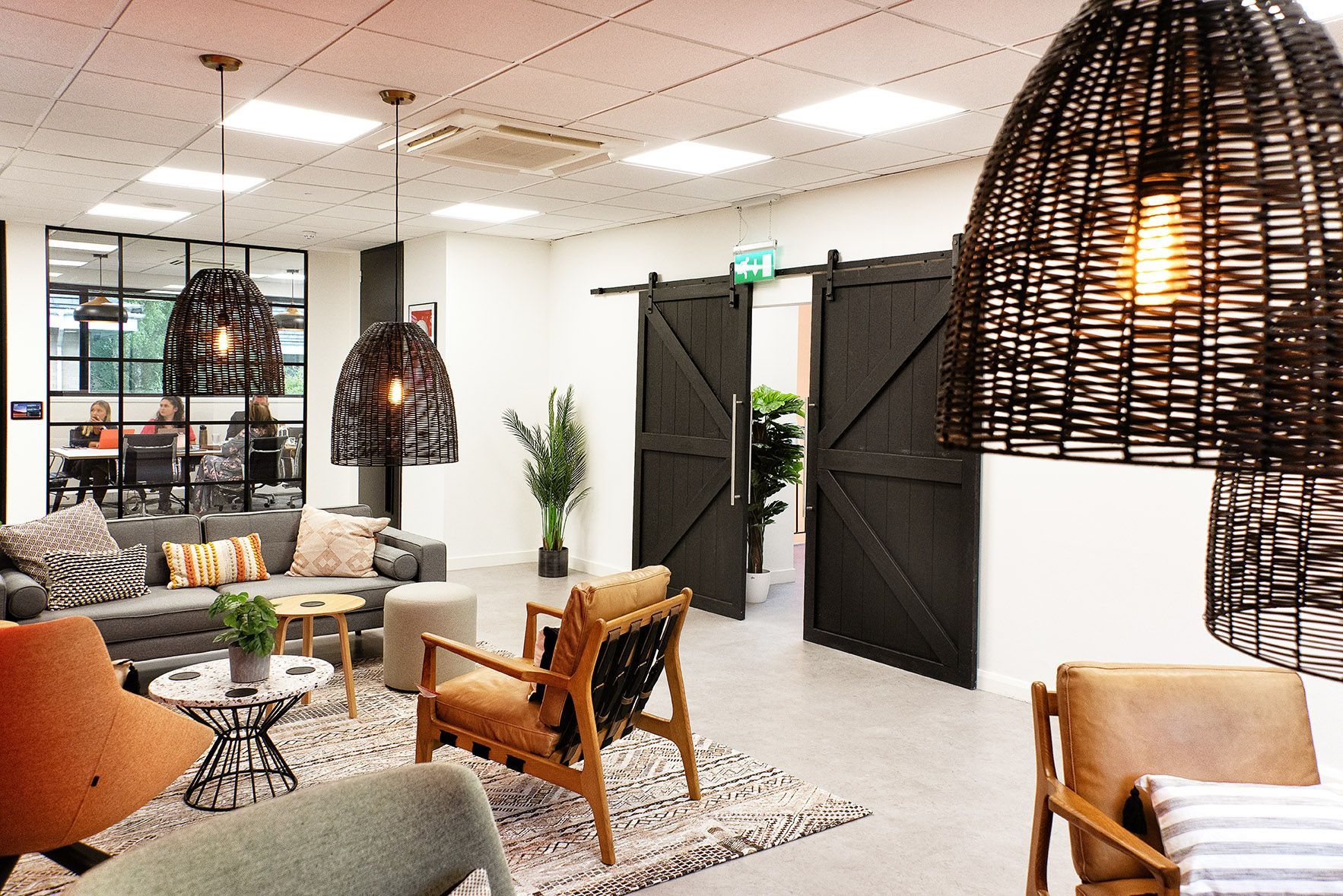 A living room with a couch , chairs , tables and wicker lamps.
