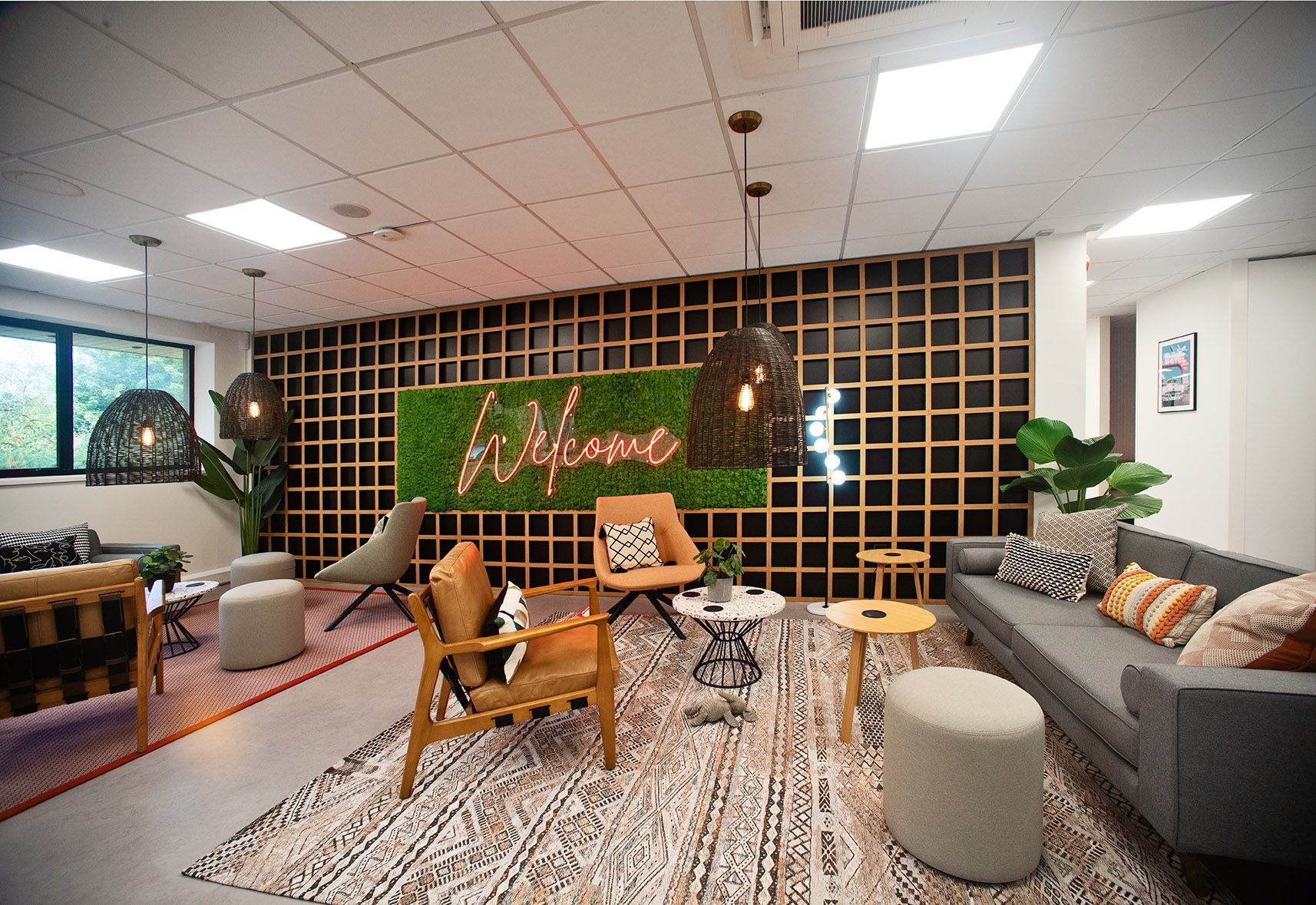 A living room with a couch , chairs , tables and a neon sign on the wall.