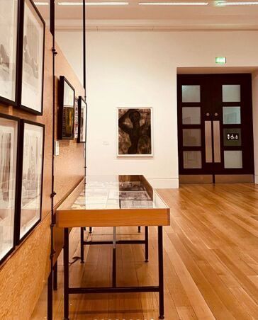 A table in a museum with a picture on the wall behind it