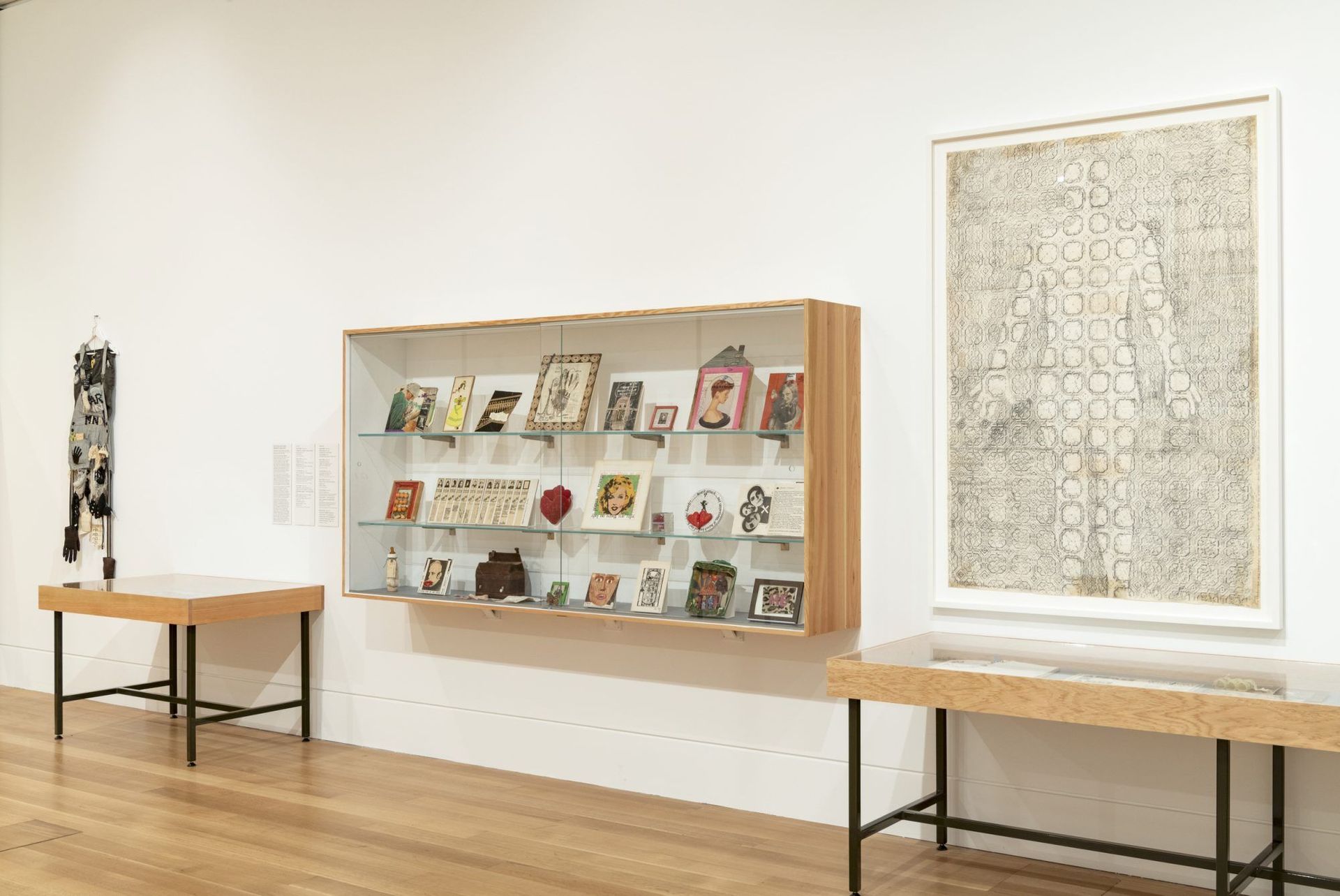 There are two tables and a shelf with a lot of art on it.