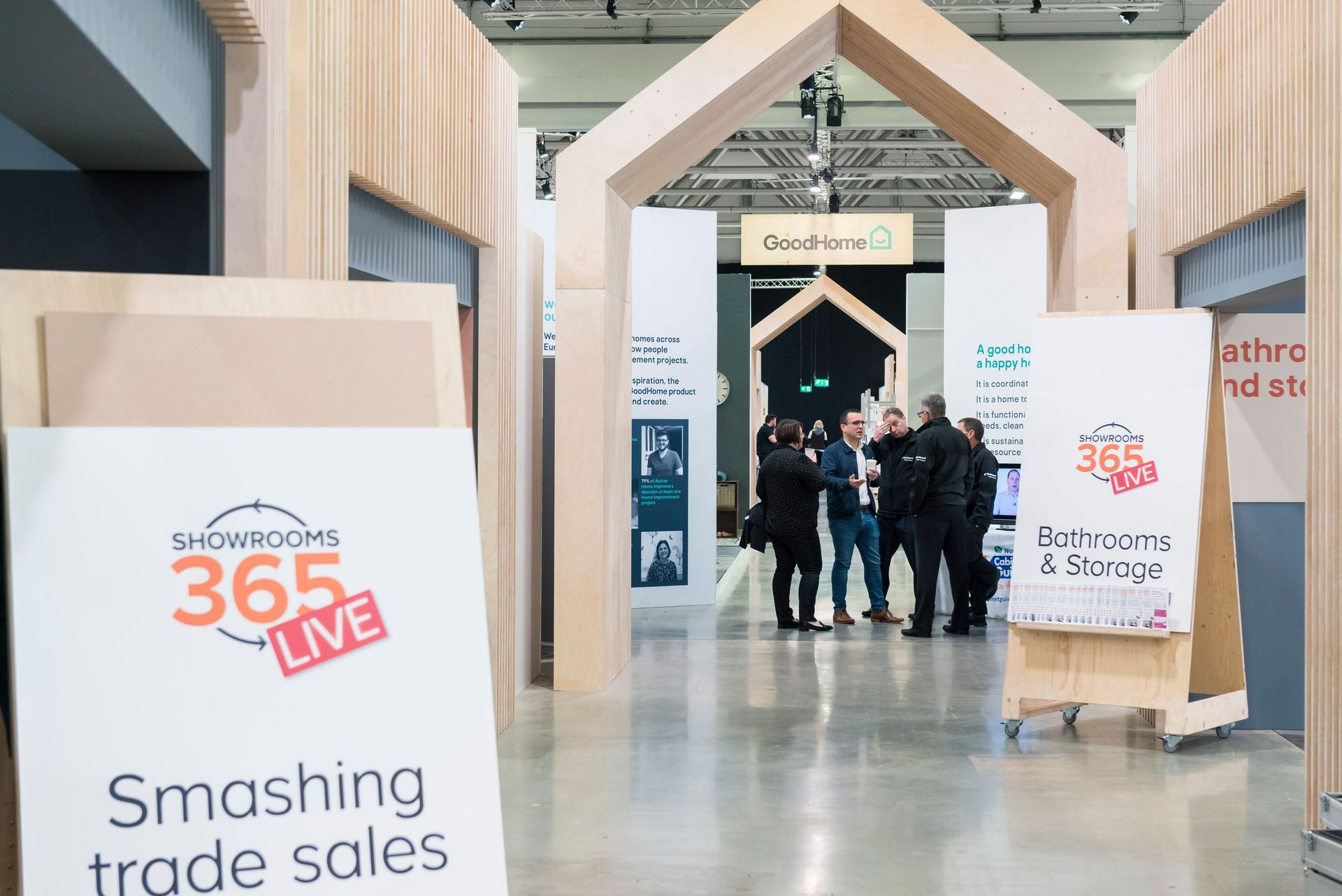 A group of people are standing in a room with a sign that says smashing trade sales.
