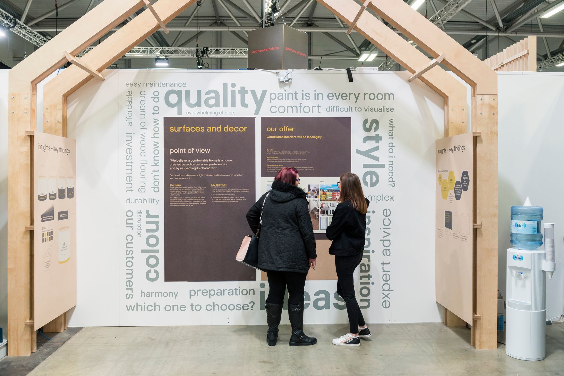 Two people are standing in front of a wall that says quality and style.