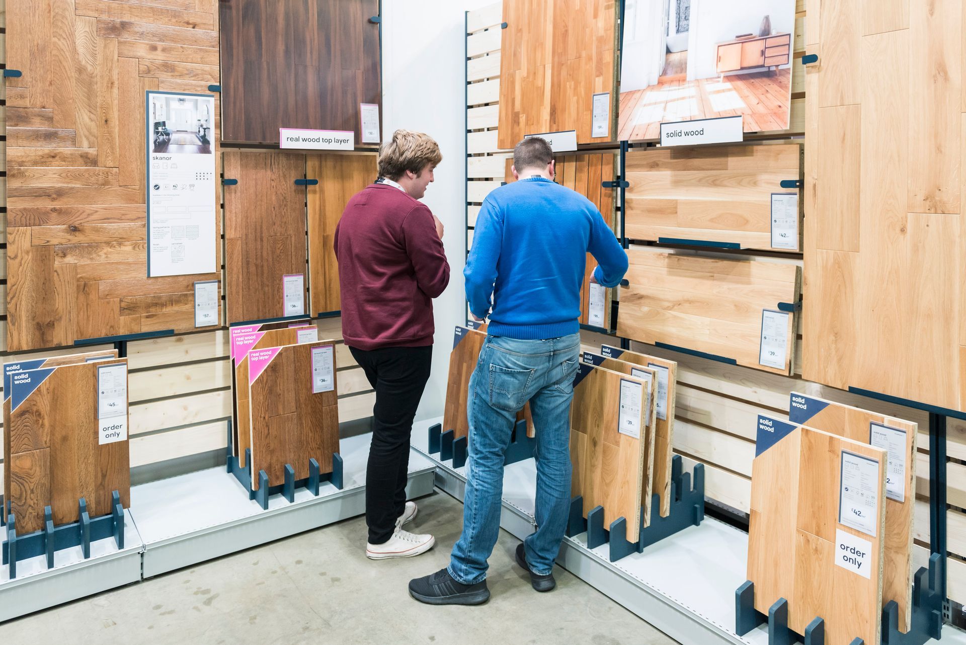 Two people are looking at wooden floors in a store.