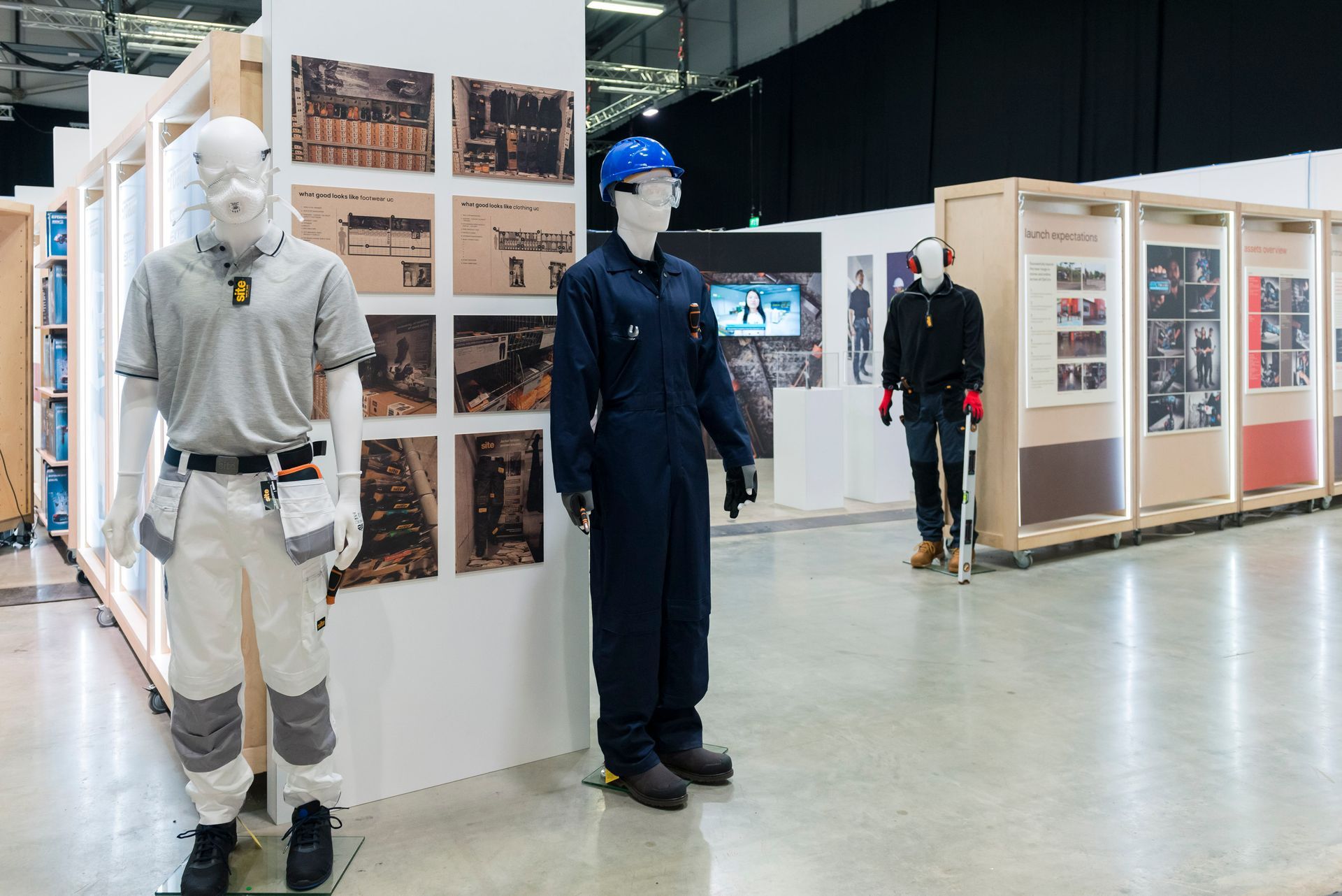 Two mannequins wearing hard hats and overalls are standing next to each other in a room.