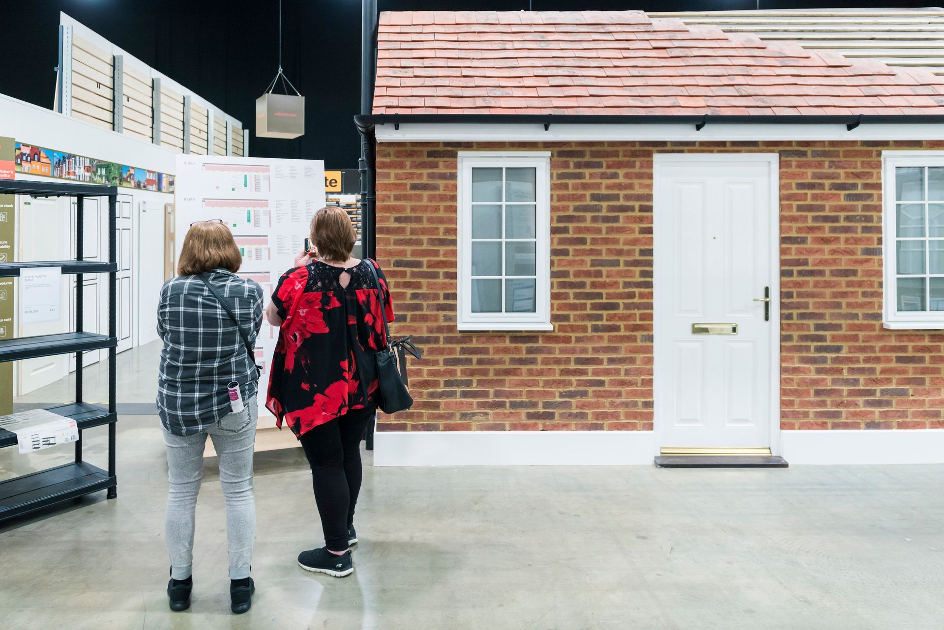 Two women are standing in front of a small brick house.