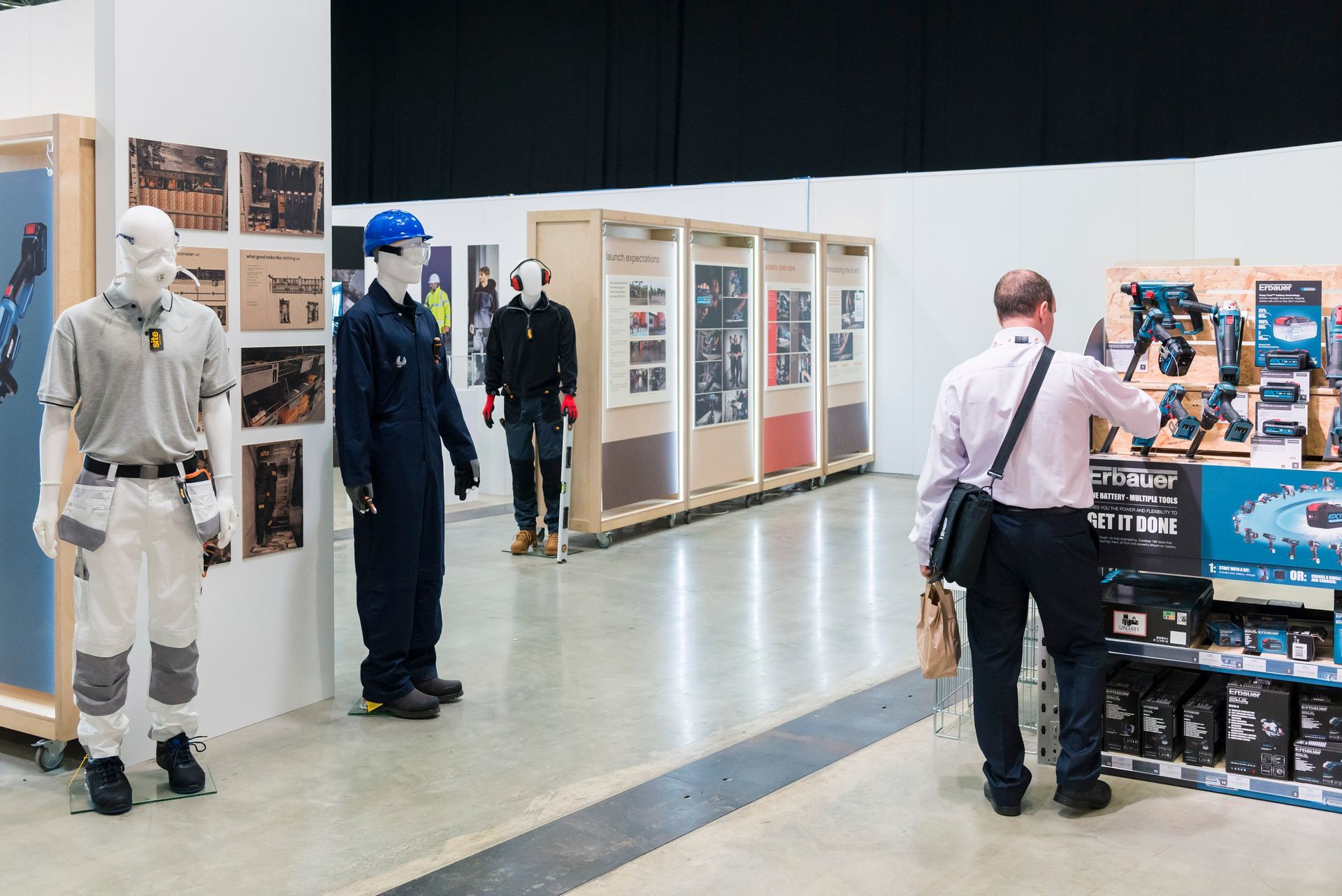 A man is looking at a display of work clothes in a store.