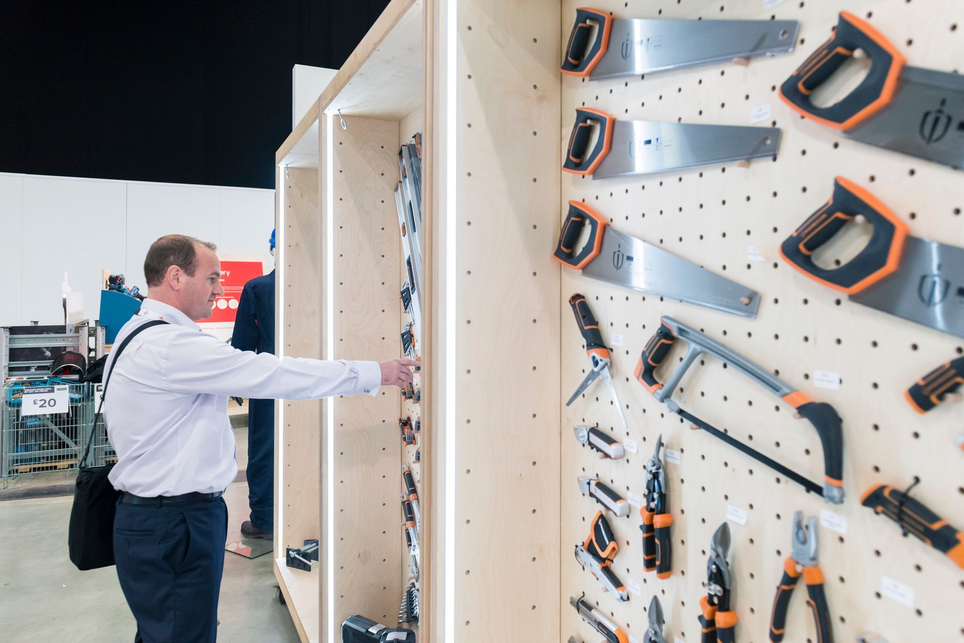 A man is standing in front of a wall of tools.
