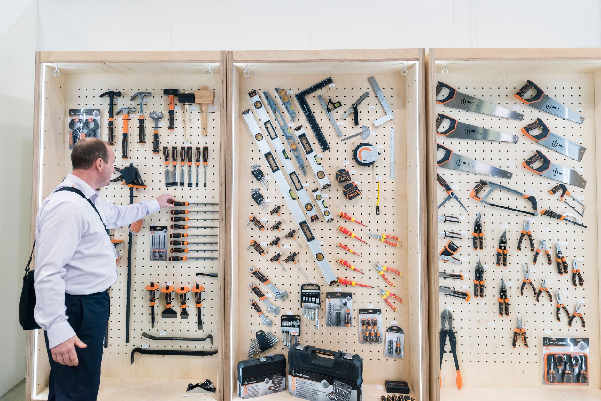 A man is looking at a wall of tools in a store.