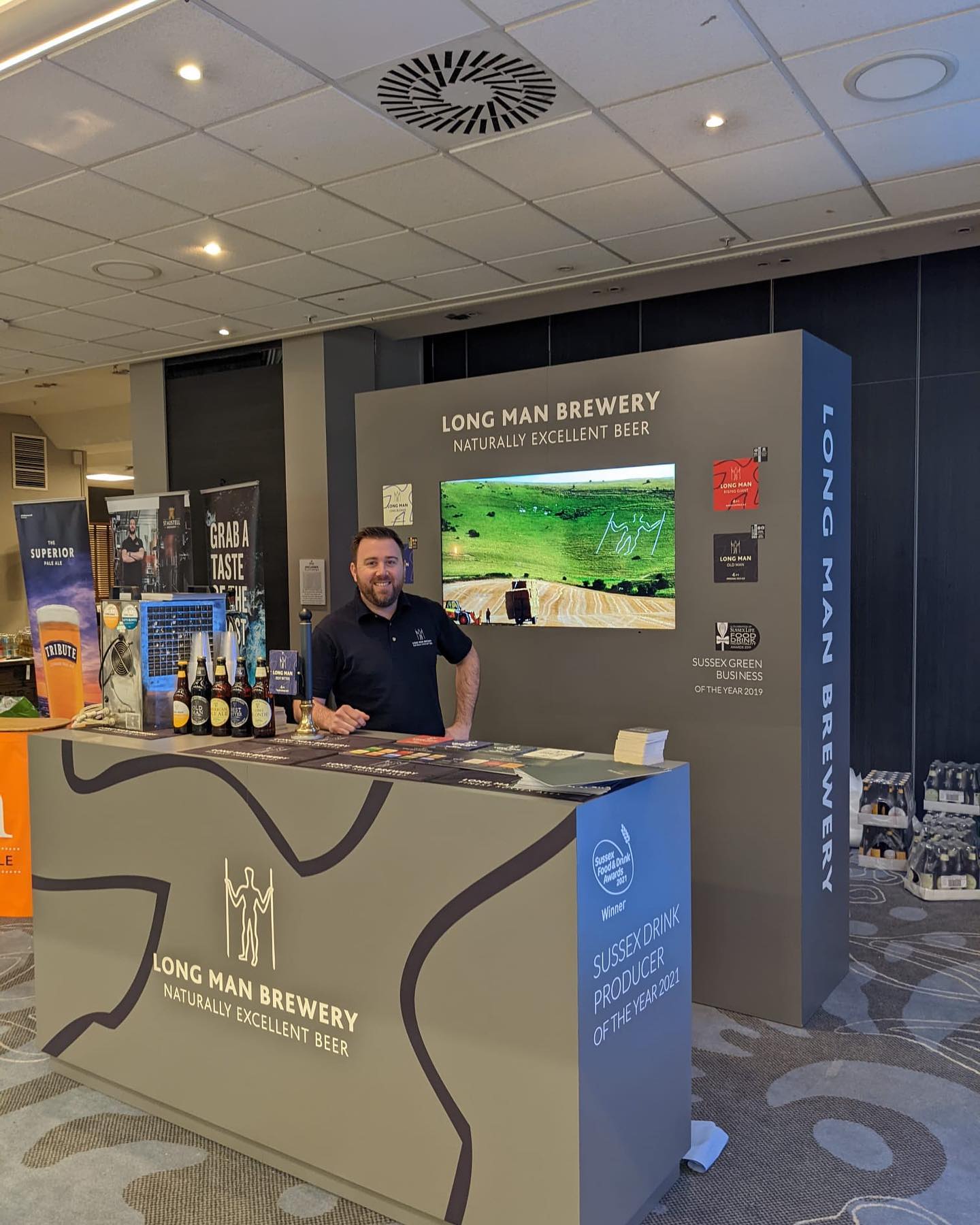 A man is standing behind a long island brewery counter