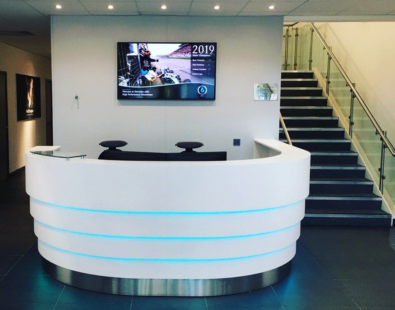 A reception area with stairs and a flat screen tv on the wall