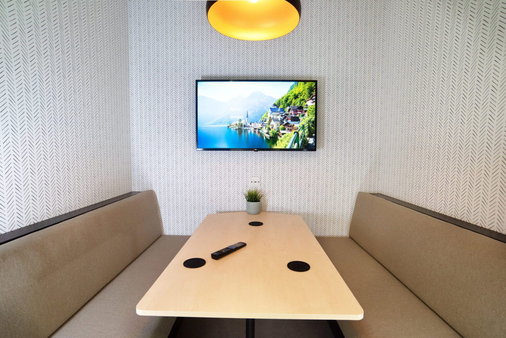 A small room with a table and a television on the wall.