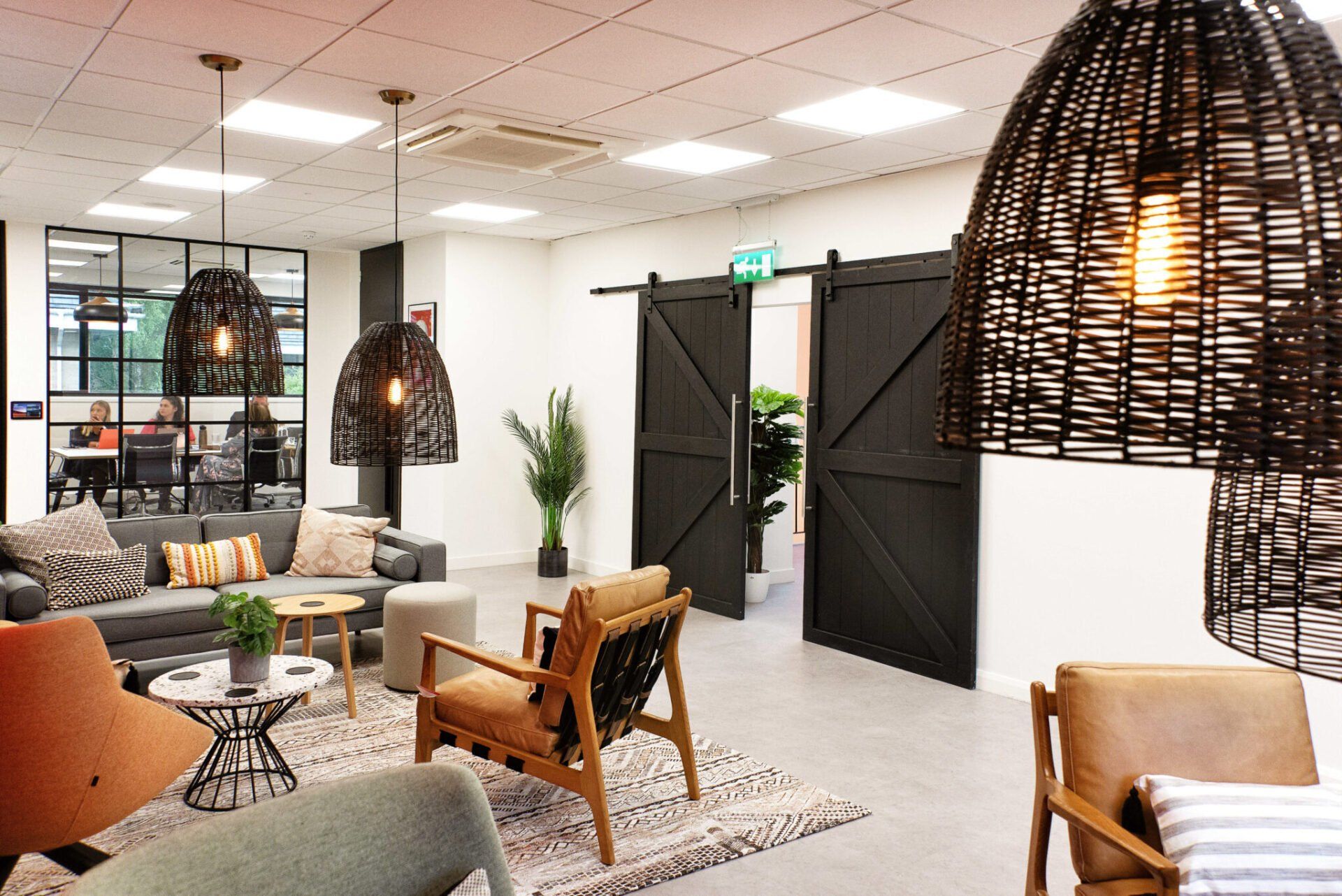 A living room with a couch , chairs , tables and wicker lamps.