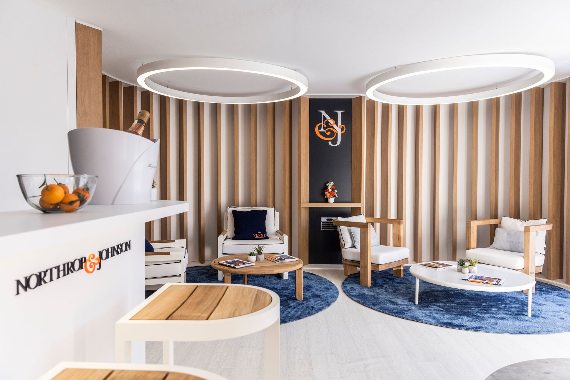 A living room with a couch , chairs , tables and a bucket of champagne.