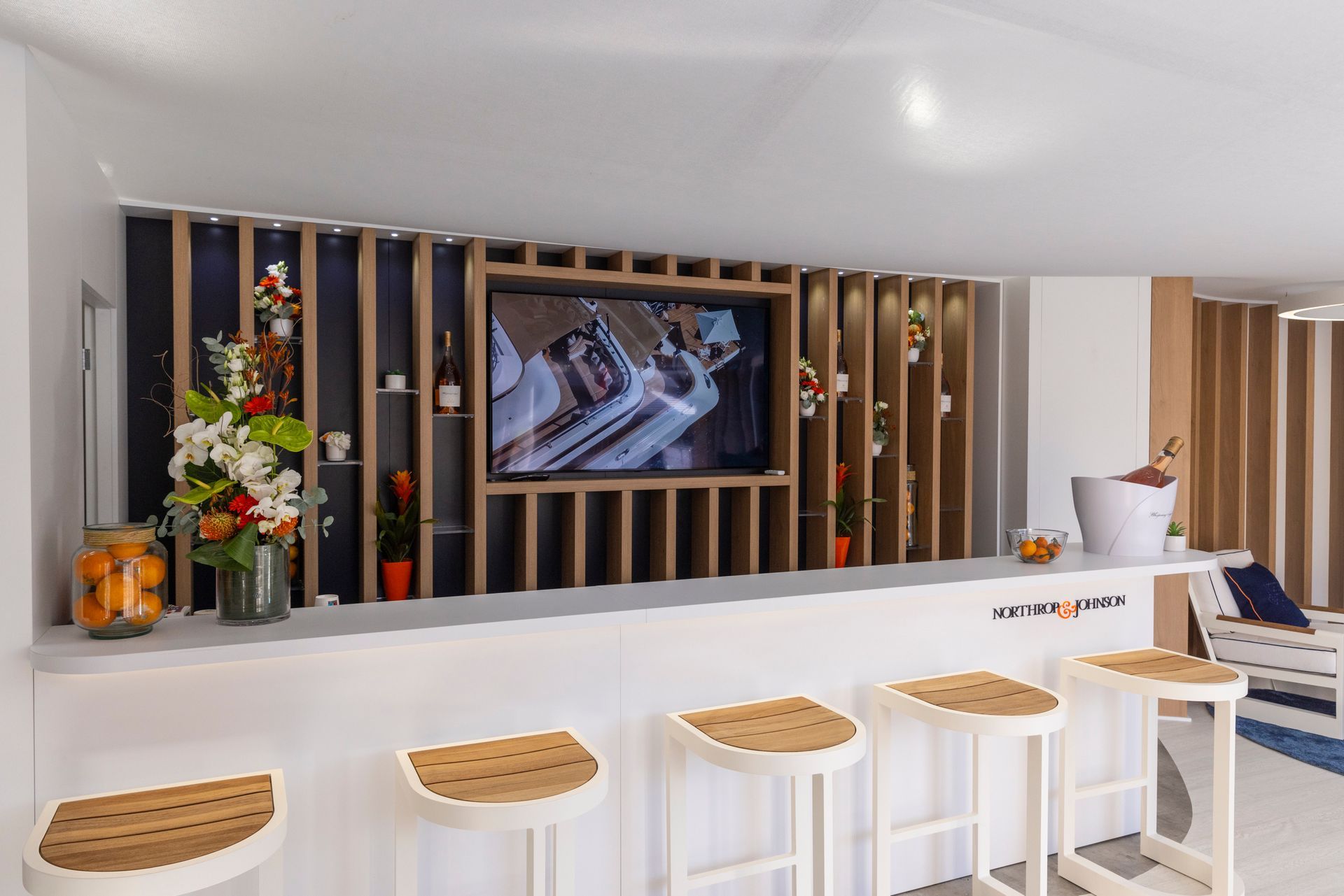 A bar with stools and a television on the wall.