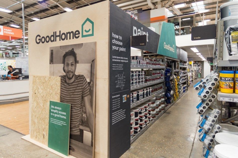 A man is standing in front of a good home sign in a store.