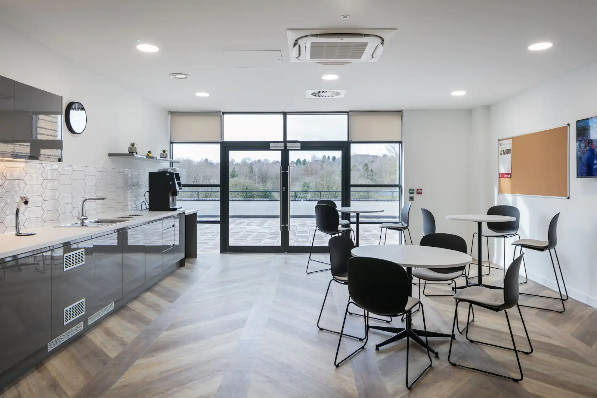 A kitchen with tables and chairs and a large window.