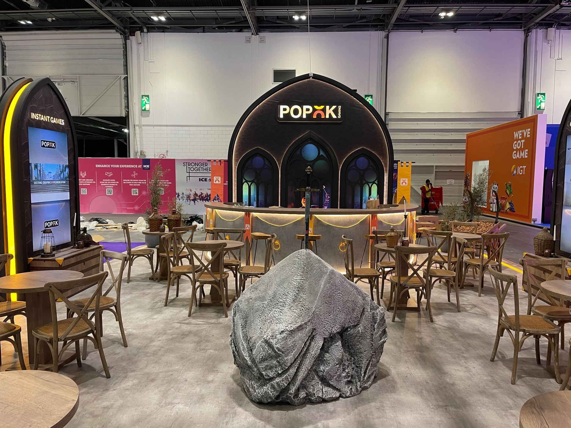 A large rock is sitting in the middle of a room with tables and chairs.