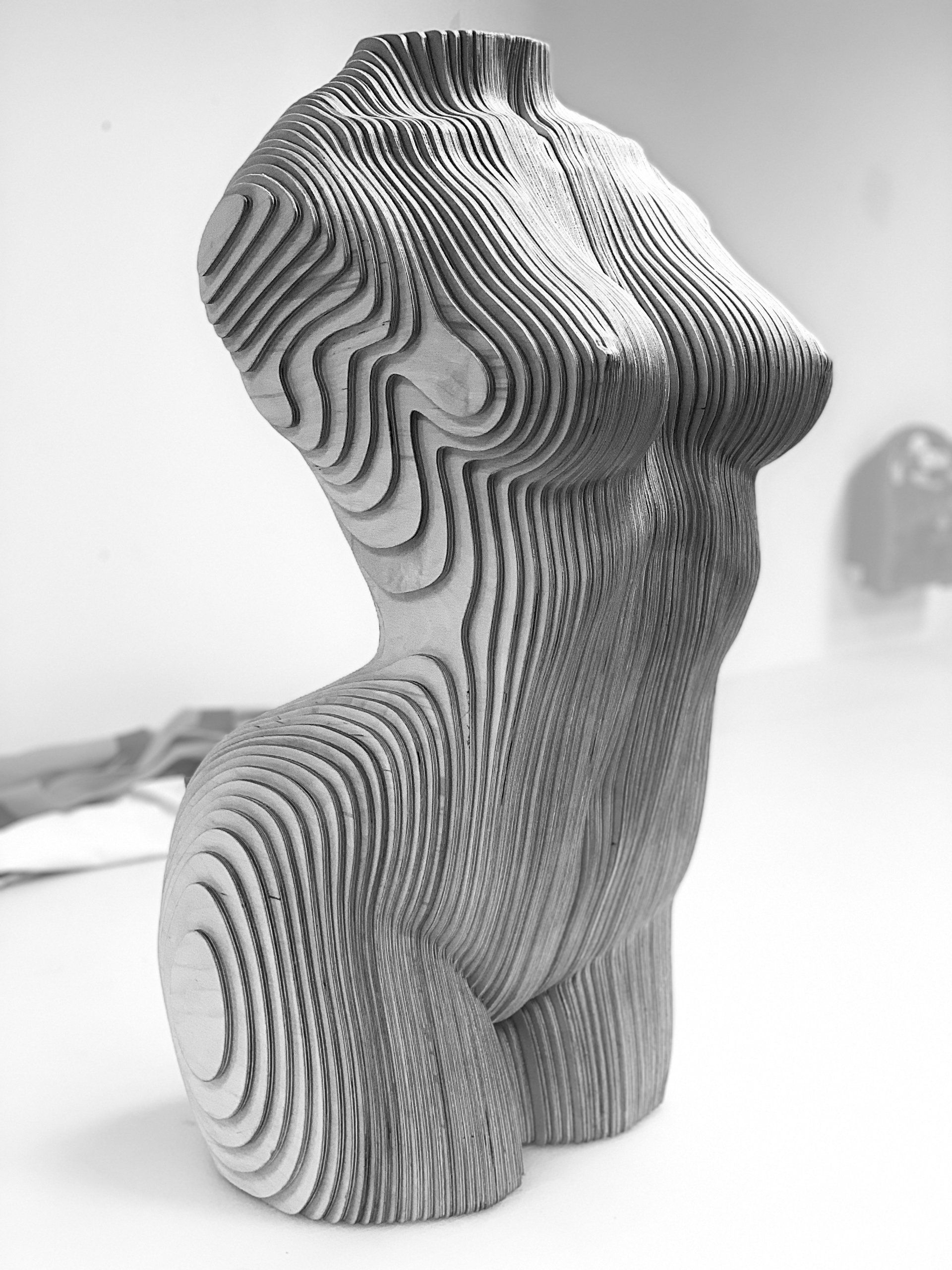 A black and white photo of a wooden sculpture of a woman 's torso.