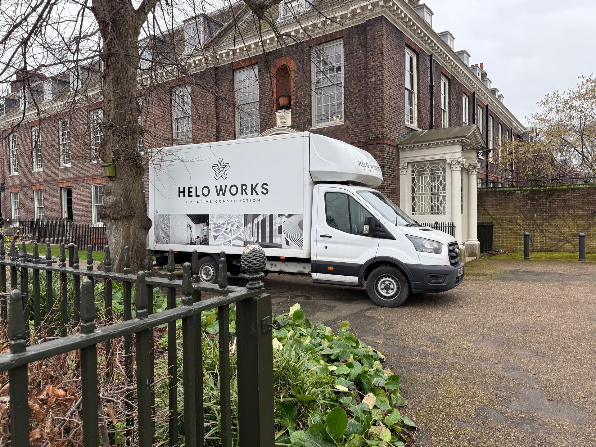 A white van is parked in front of a large brick building.