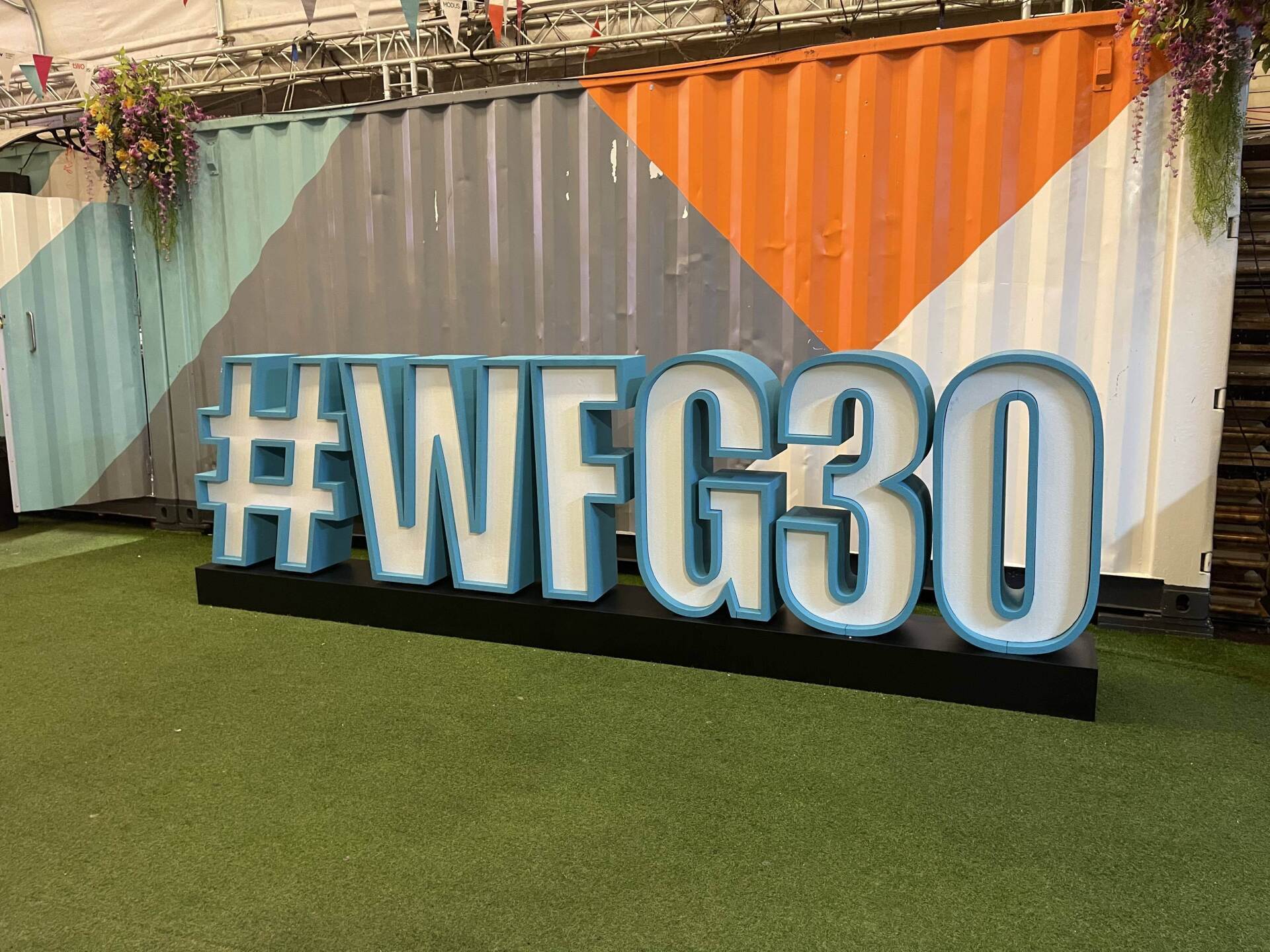 A large sign that says # wfg30 is in front of a shipping container.