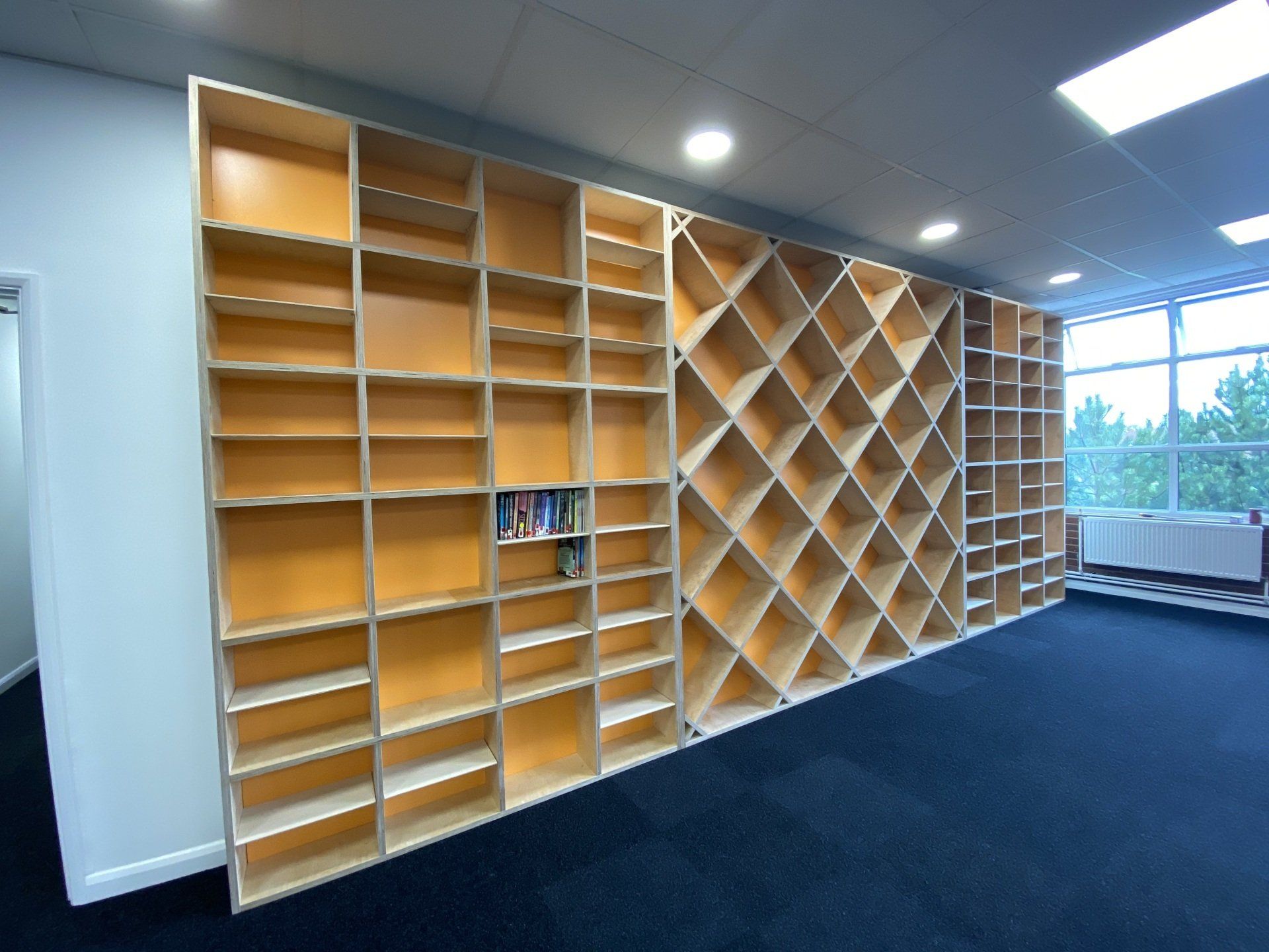 A large wall of shelves in a room with a window.