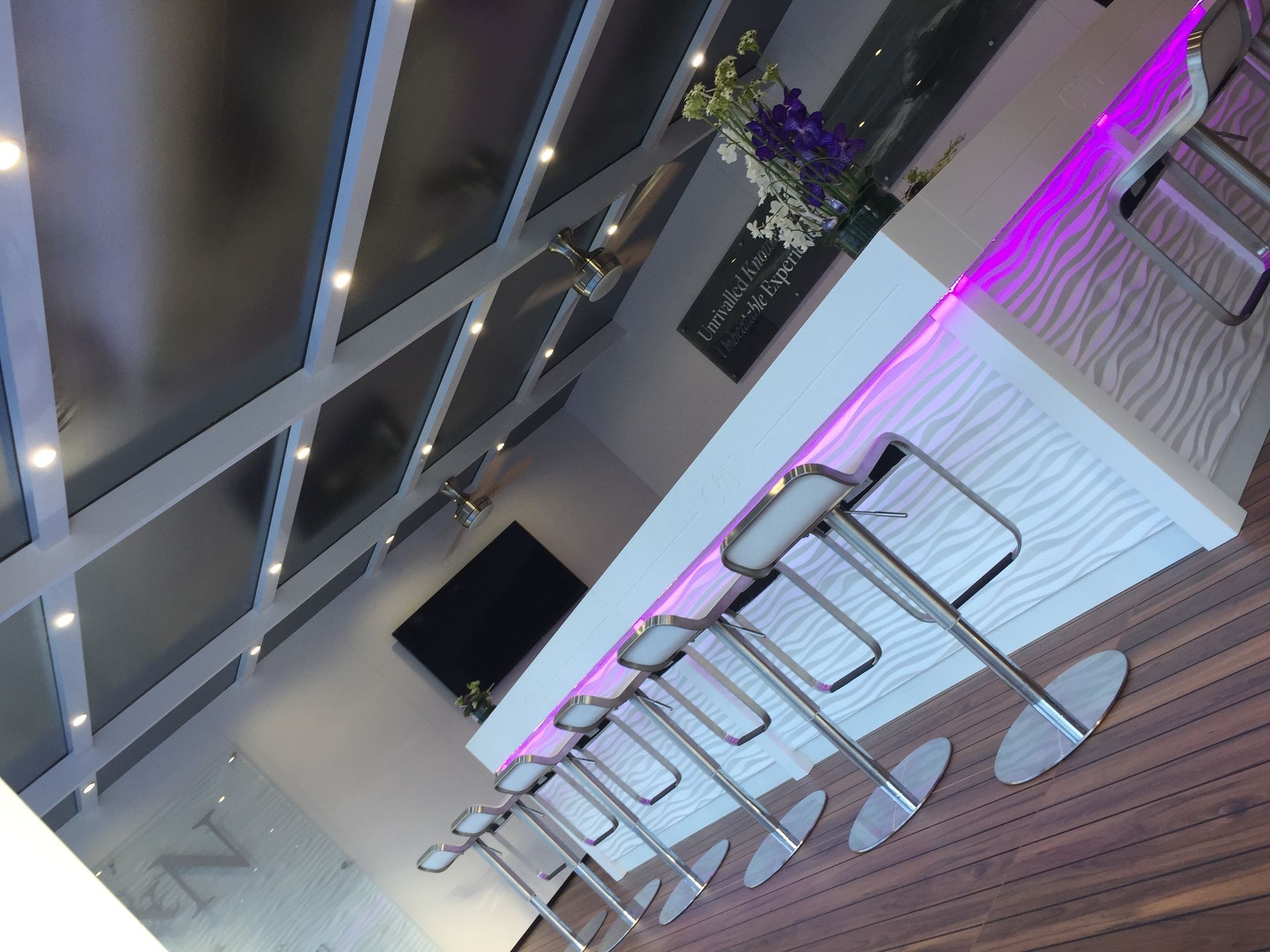 A row of bar stools are lined up in front of a white counter