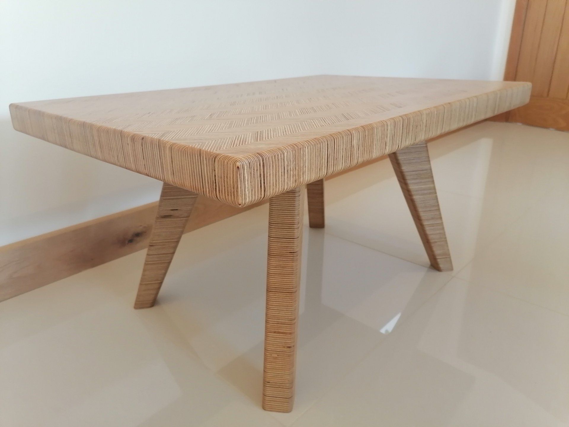 A wooden table with three legs is sitting on a tiled floor.