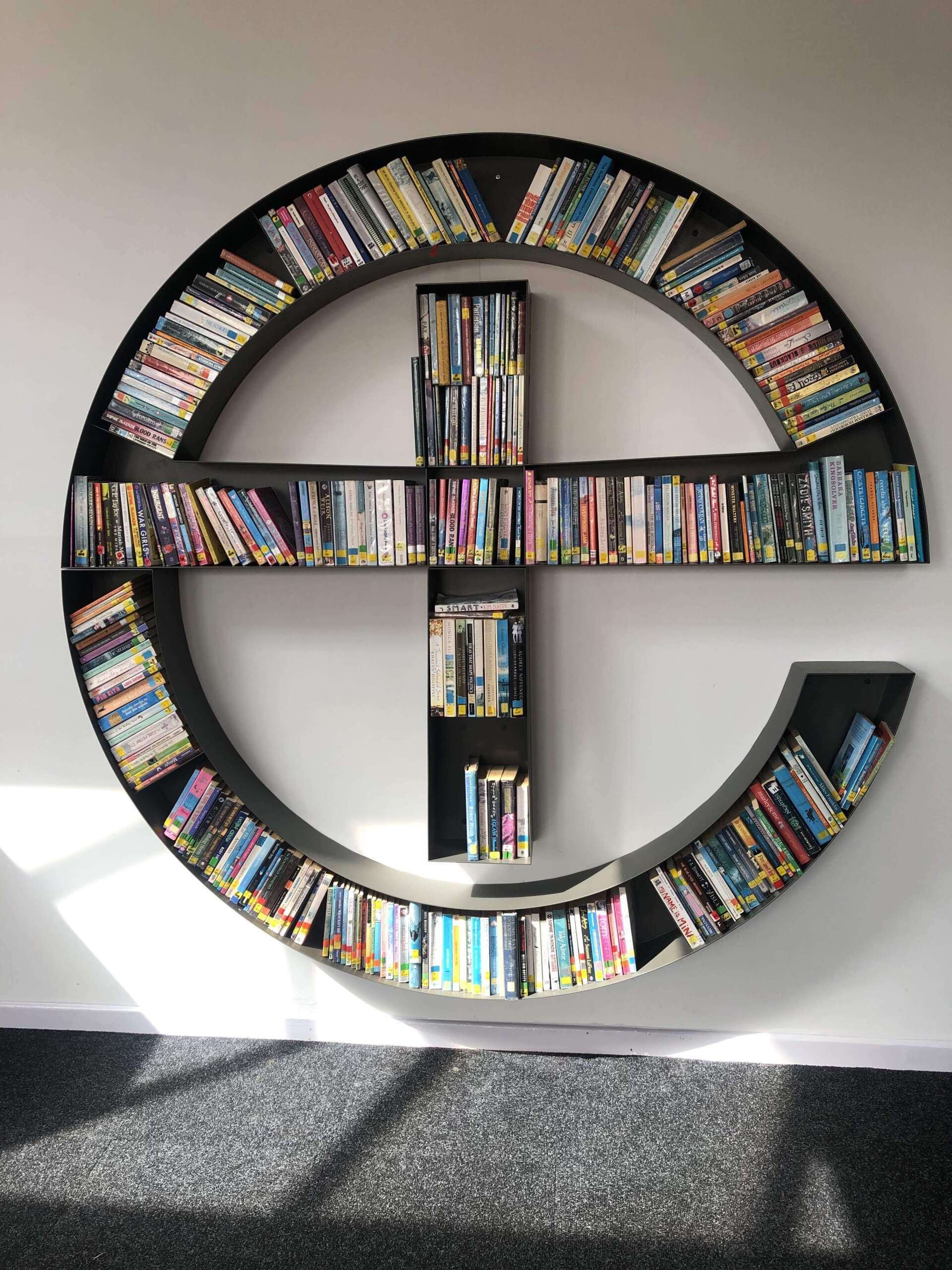 A bookshelf in the shape of a cross filled with books