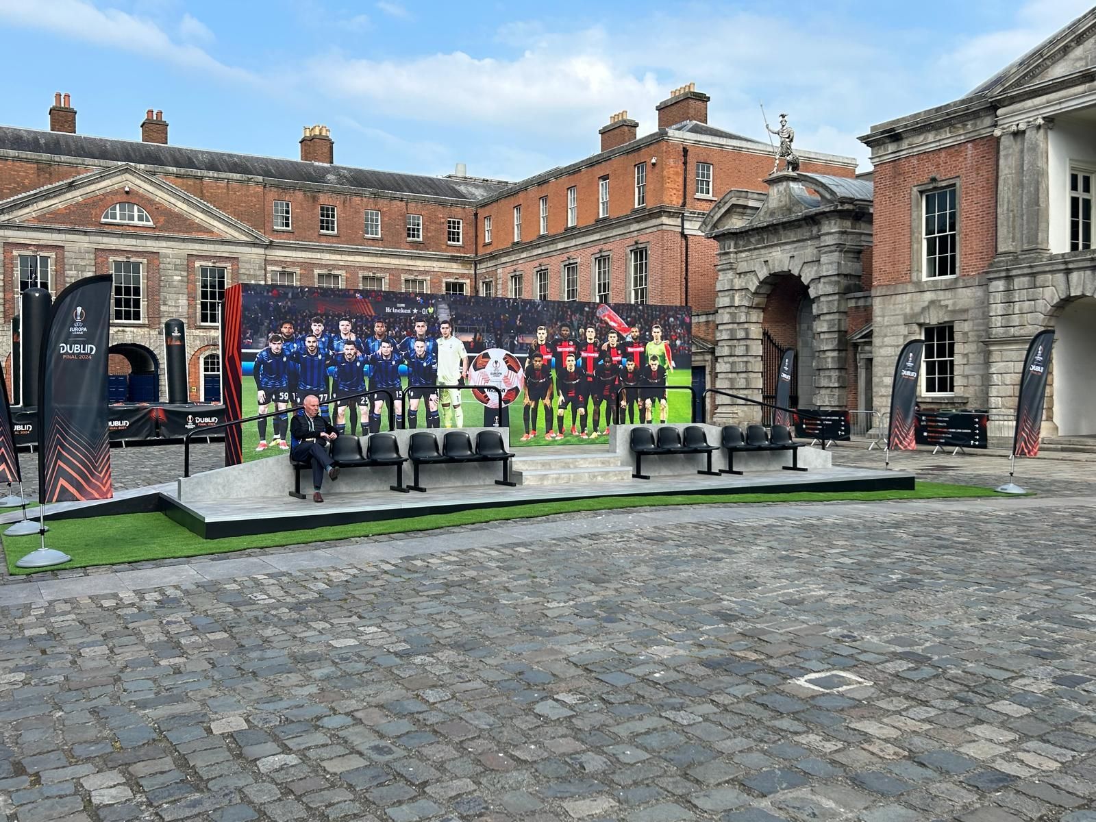 A large billboard with a picture of a soccer team on it is in front of a building.