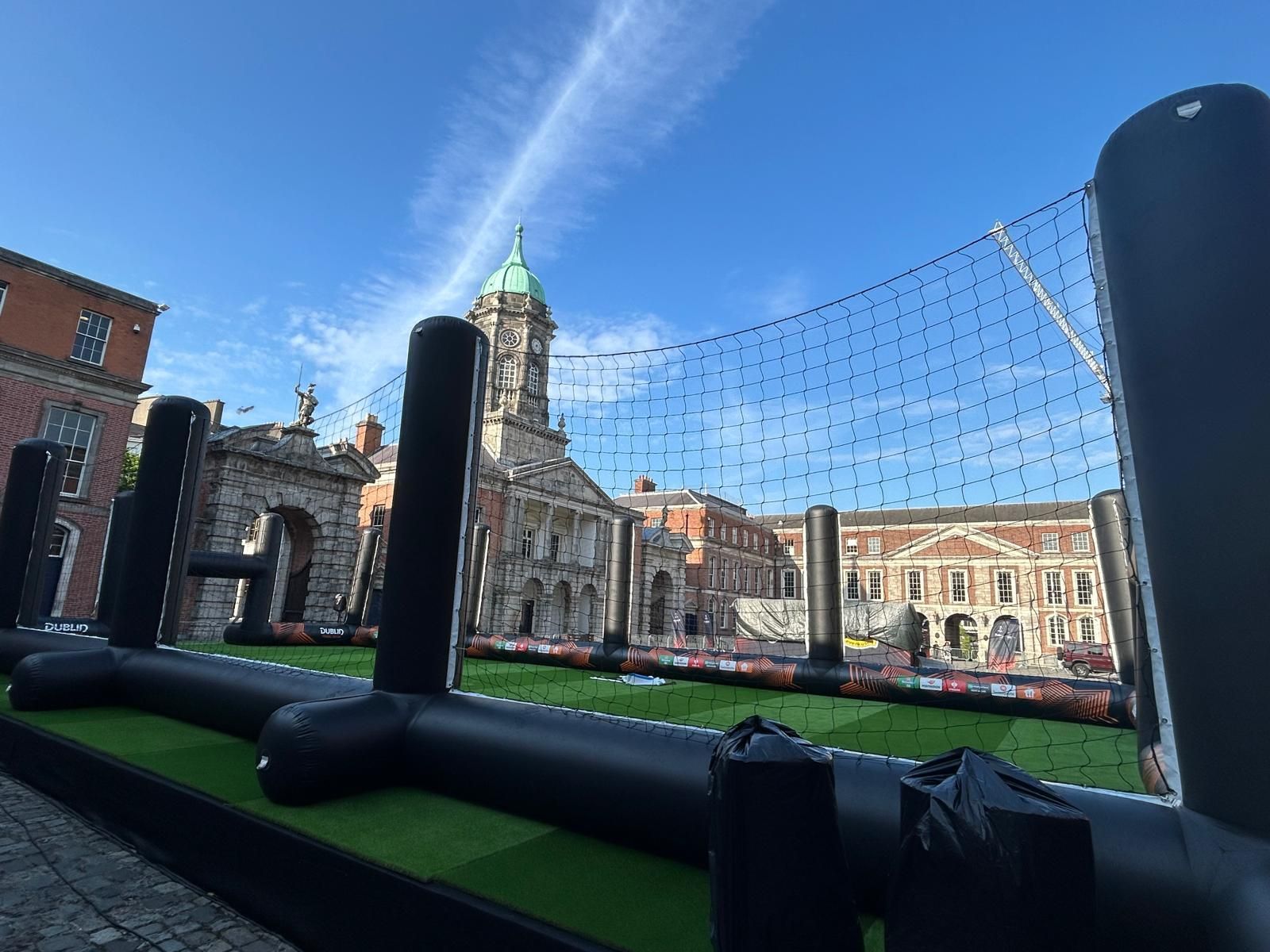 A large inflatable soccer field with a building in the background.