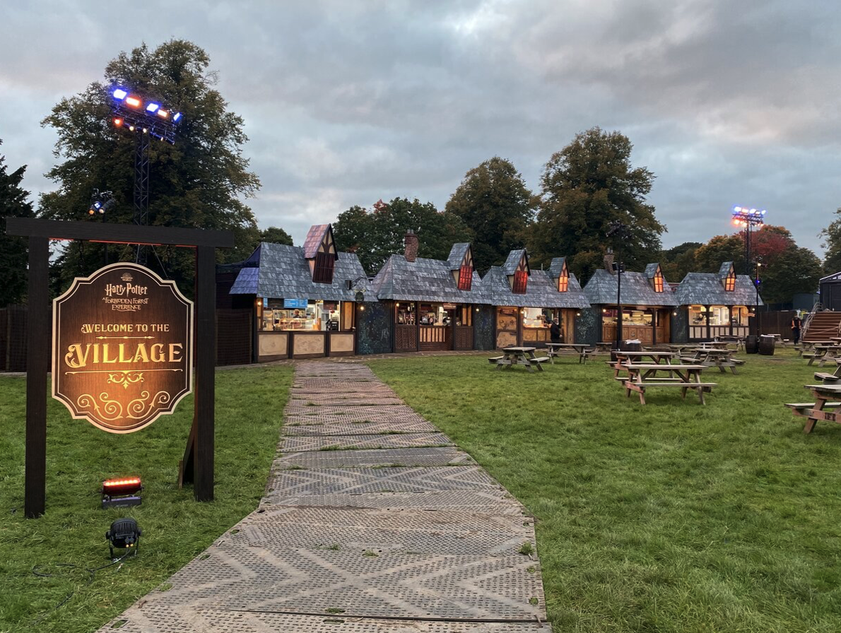 A sign that says evil village is in front of a row of houses.