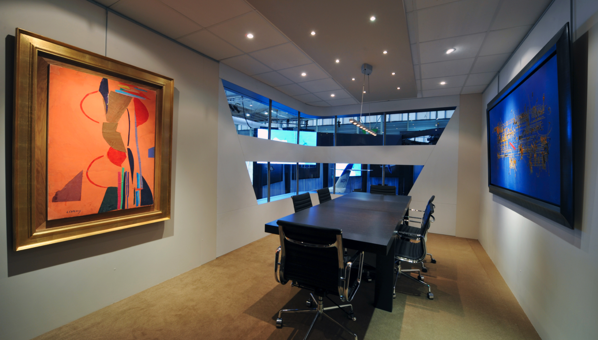 A conference room with a table and chairs and a painting on the wall