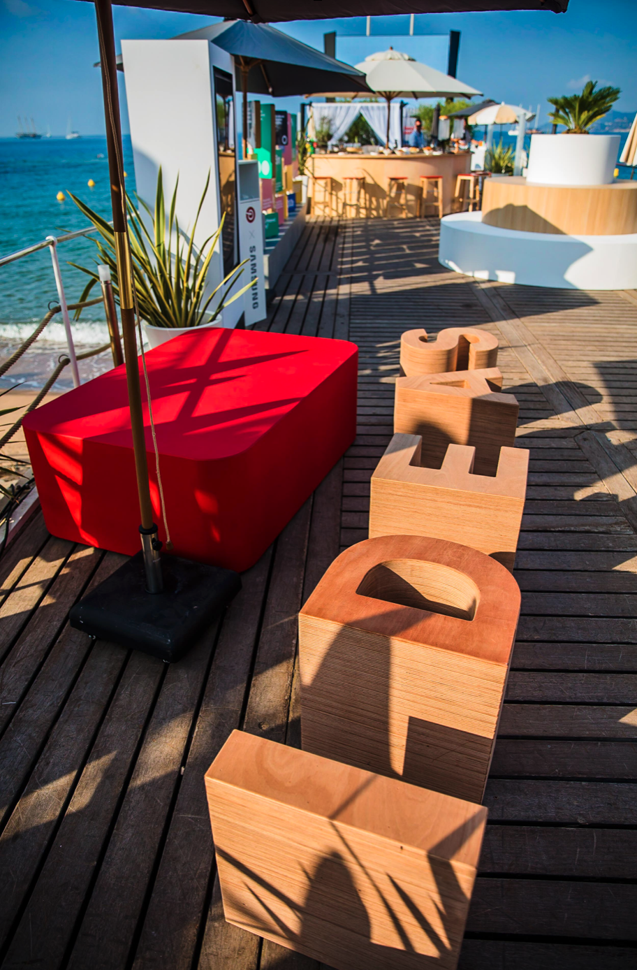 A wooden deck with a red ottoman and wooden letters that spell out the word peace