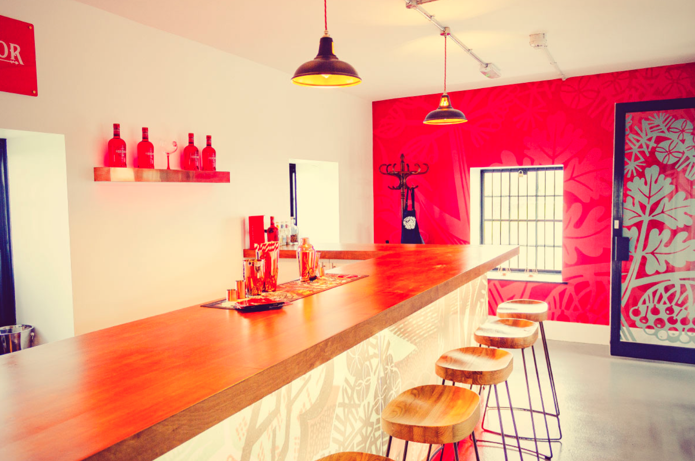 A long wooden bar with stools in a room with a red wall.